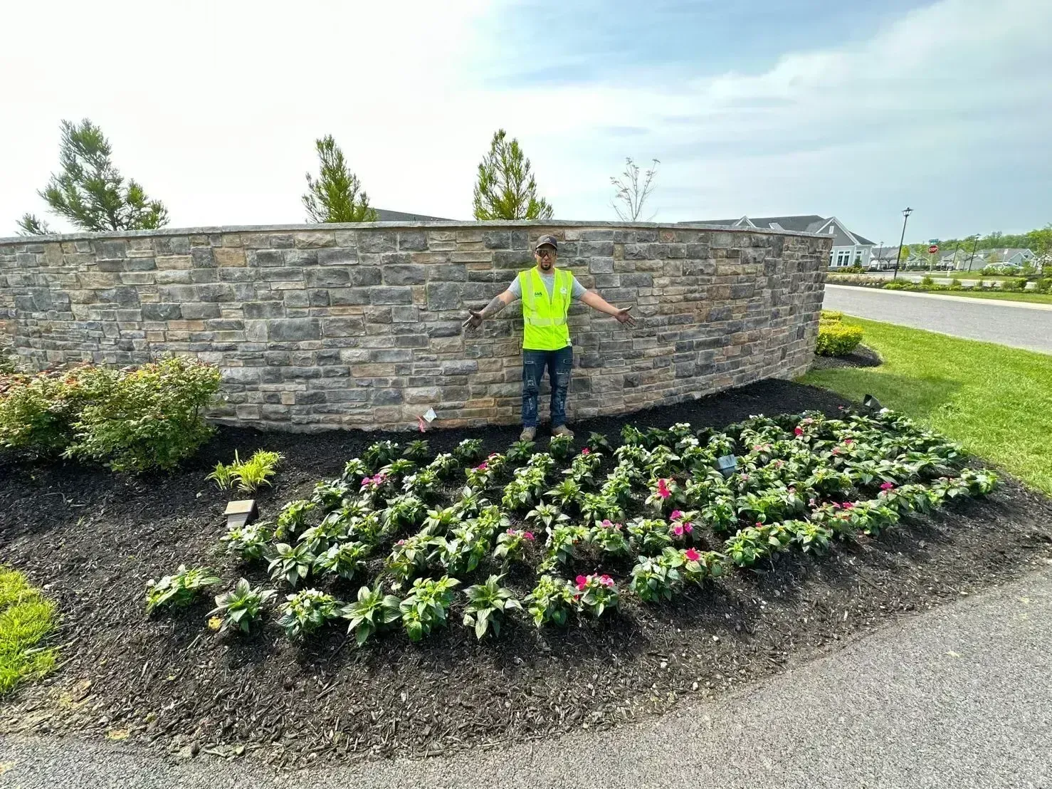 an R&S Property Services worker posing behind a recently installed flower bed