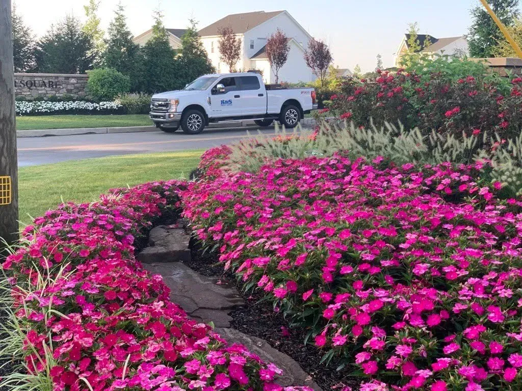 an R&S Property Services pickup truck parked behind a freshly installed flower bed