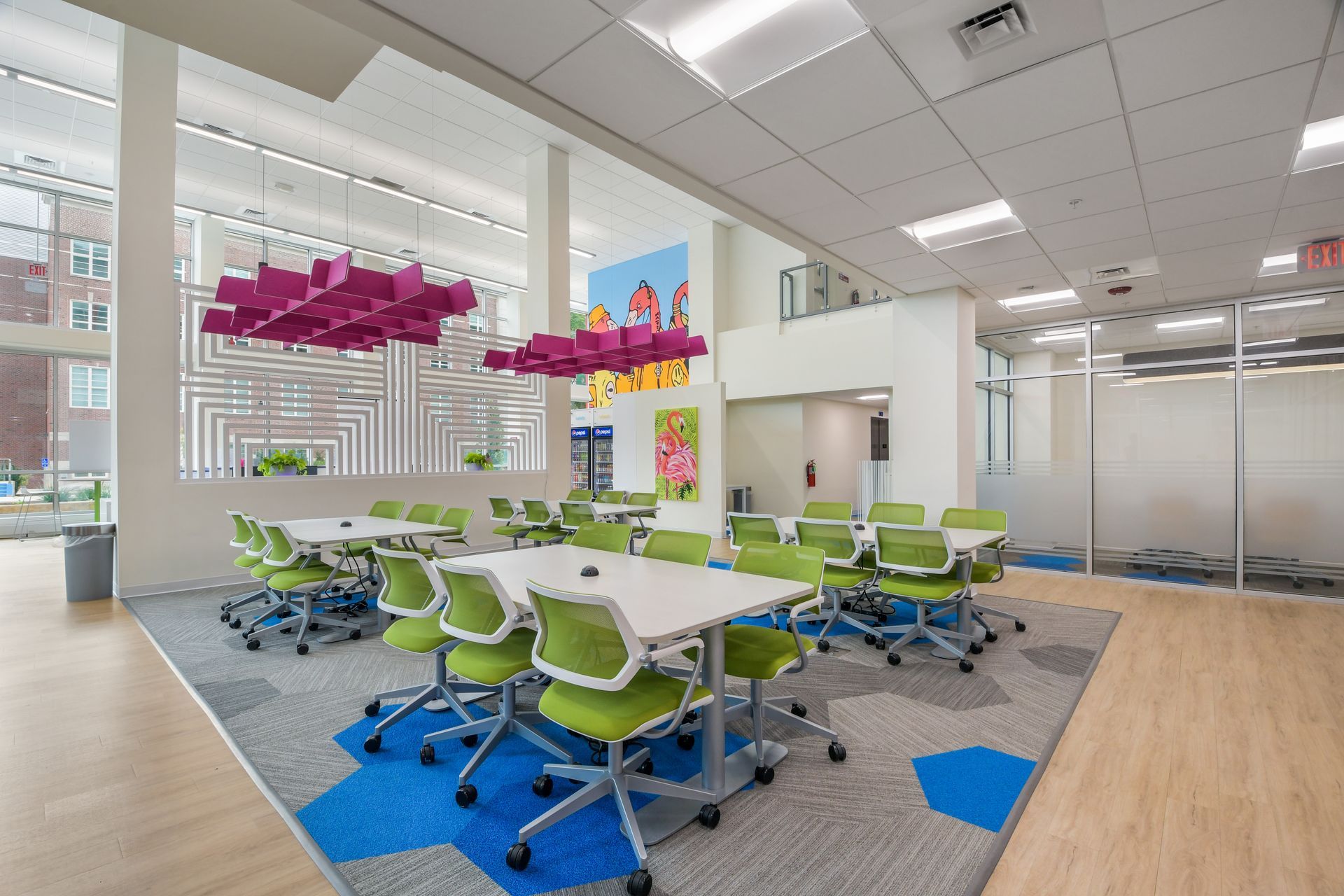 Modern classroom with tables, green chairs, and pink cloud-shaped decoration hanging from the ceiling.