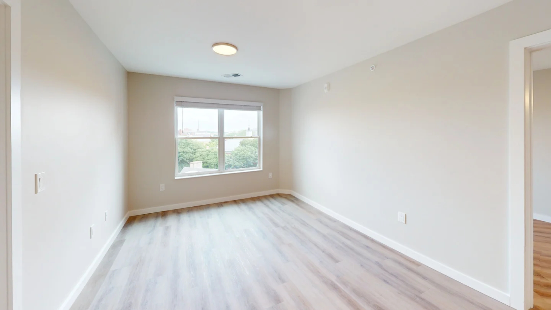 Empty room with hardwood floors, a window, and off-white walls.