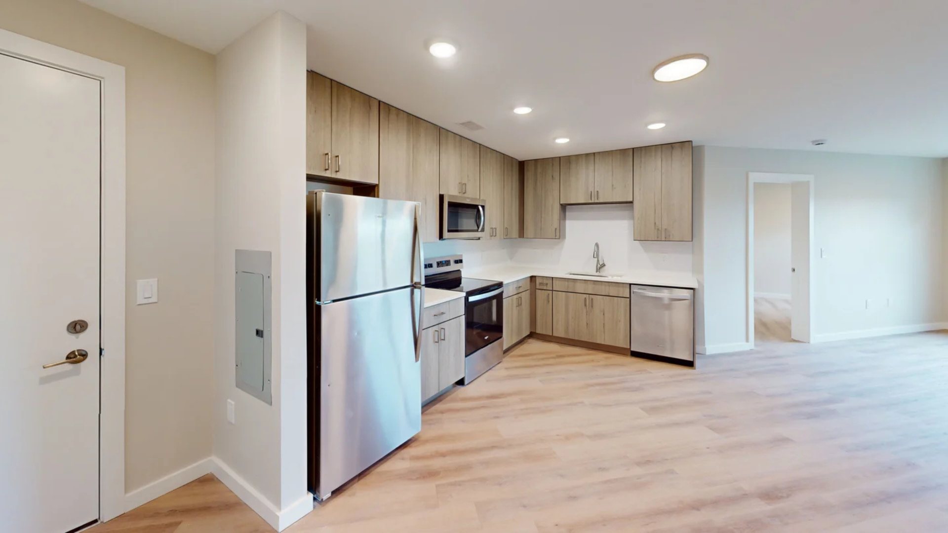 Kitchen with light wood cabinets, stainless steel appliances, and light wood flooring.