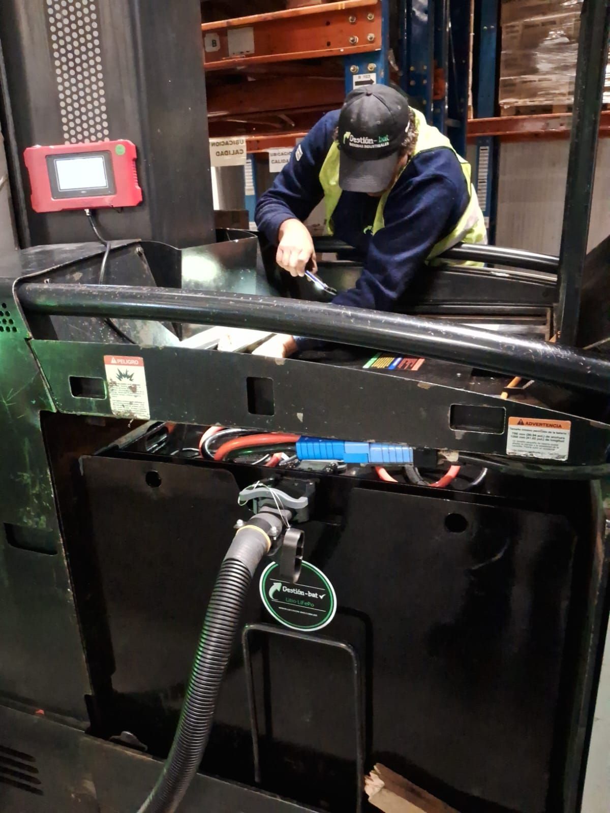 Un trabajador maneja una carretilla elevadora en un almacén, detrás de barreras de seguridad negras.