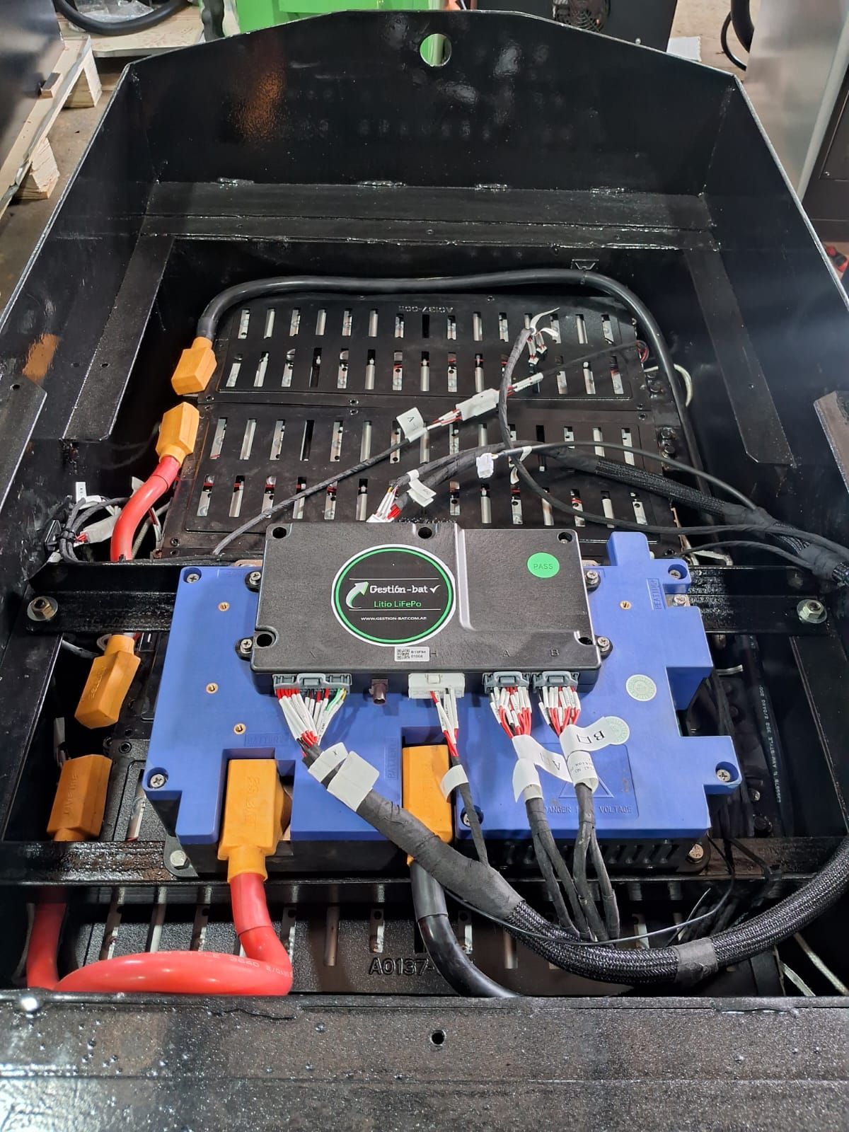 Unidad de control electrónico azul con cables montados dentro de una caja de equipos negra.