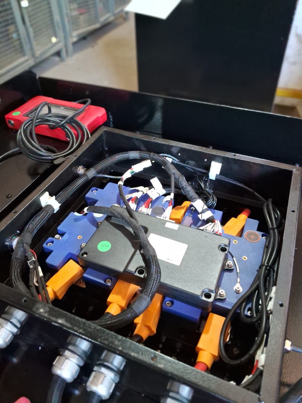 Caja de equipo abierta con componentes electrónicos azules y naranjas, cables y un dispositivo rojo en su interior.