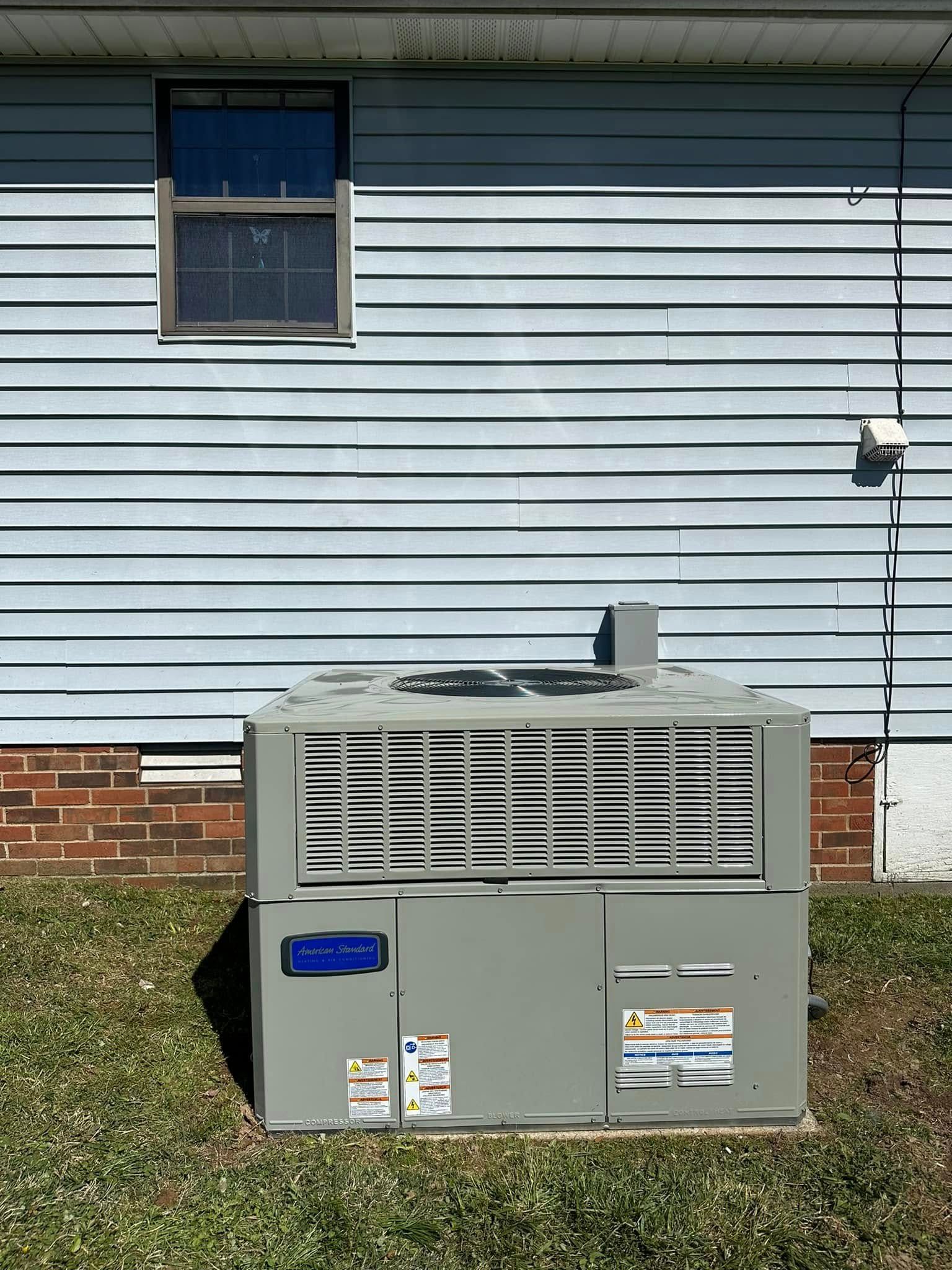 Outdoor HVAC unit beside a blue house with white siding and a small window