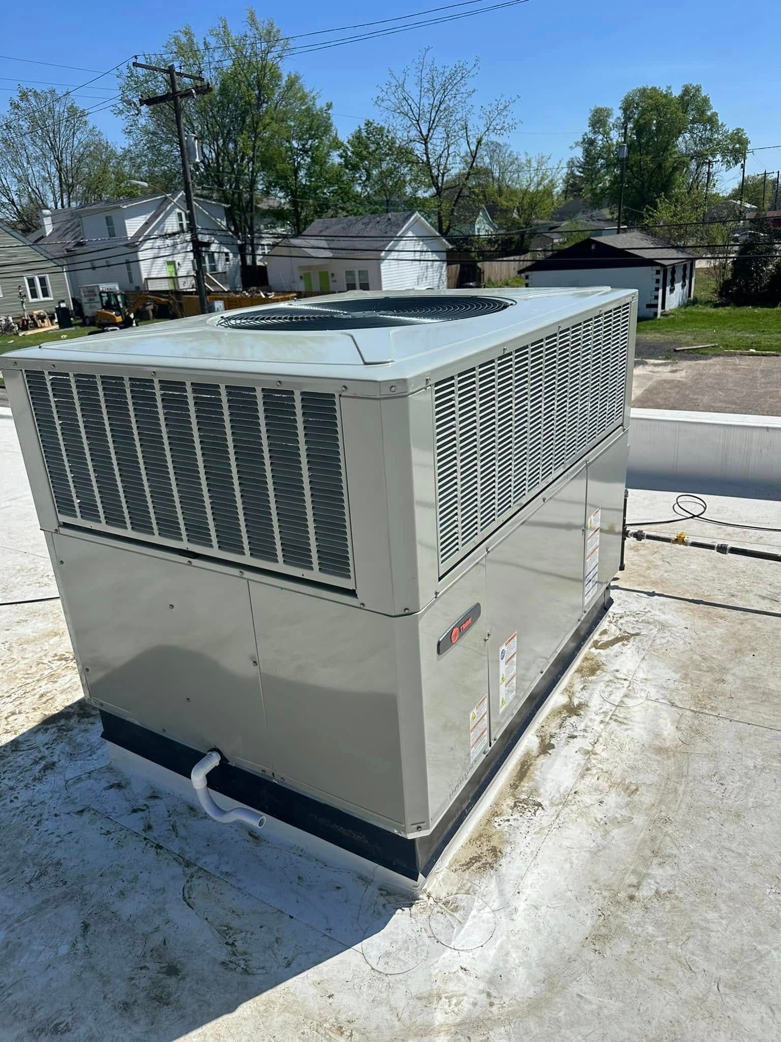 Large outdoor HVAC unit on a rooftop, with houses and trees in the background.