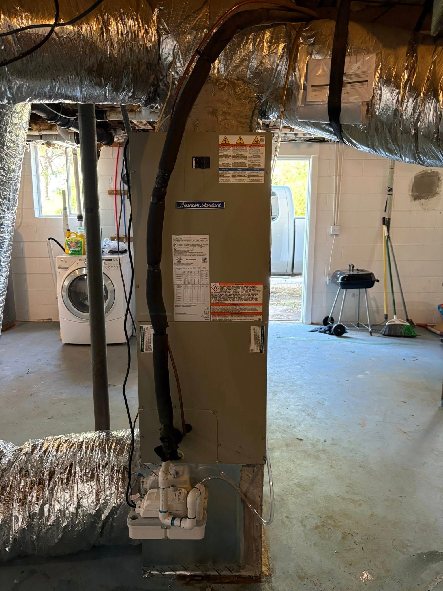 Unfinished basement with exposed ductwork and a central furnace unit.