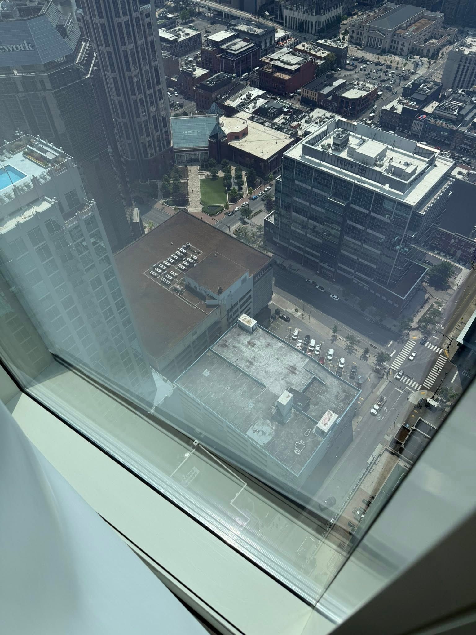 A city view through a window, showing tall buildings, rooftops, and streets below.