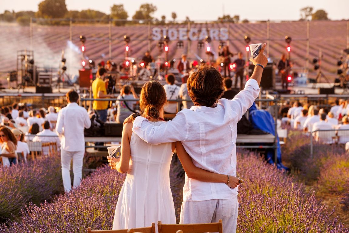Pareja disfrutando de un concierto al atardecer entre los campos de lavanda del Festival de la Lavanda en Brihuega.