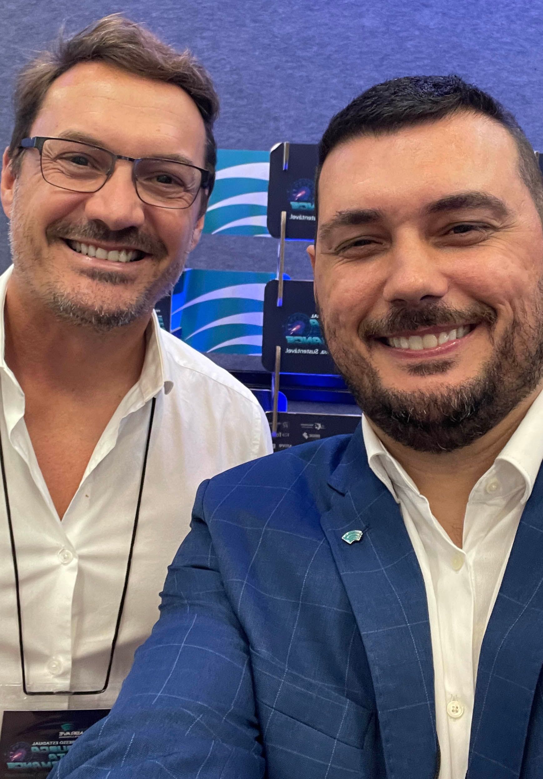 Two men are posing for a picture together and smiling for the camera.