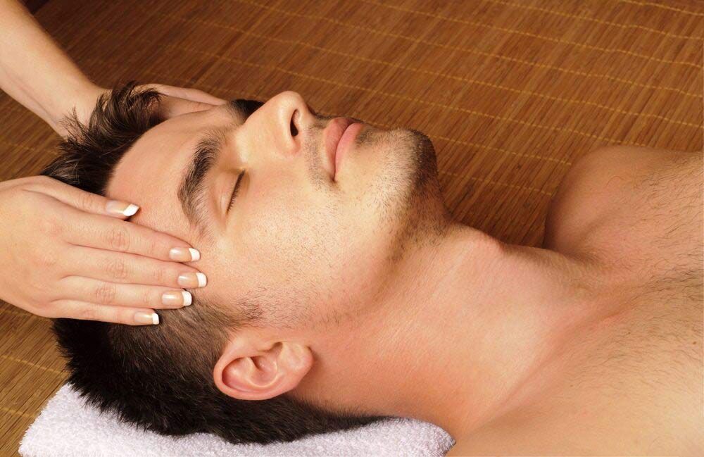 A Man is Lying On His Back on a Towel With Two Hands Placed Either Side of His Face— Phoenix Mandorla In Rockhampton City, QLD