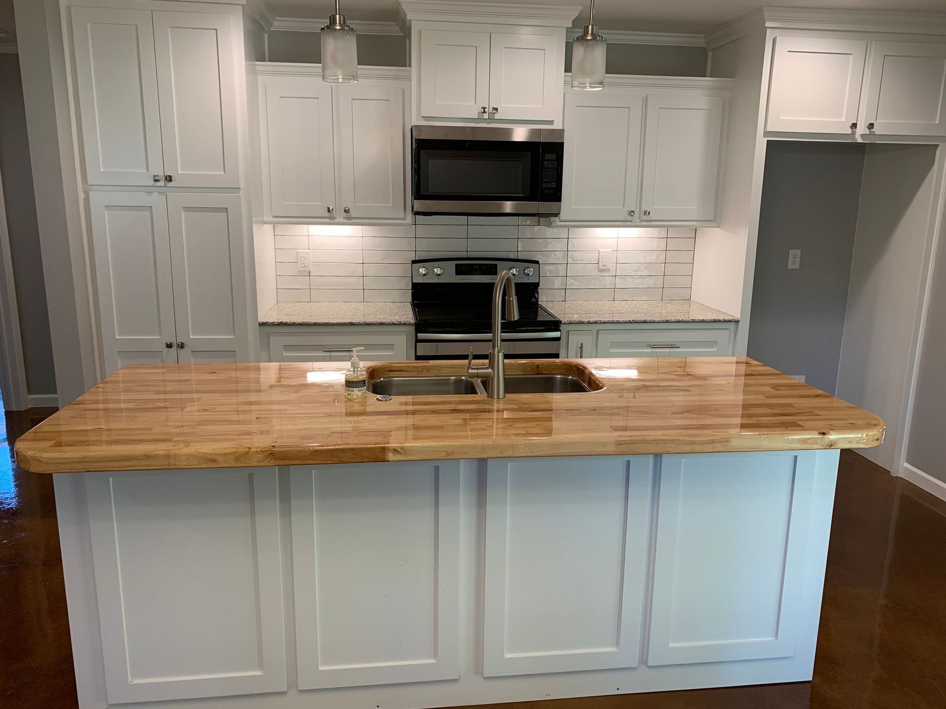 A kitchen with white cabinets and a wooden counter top.