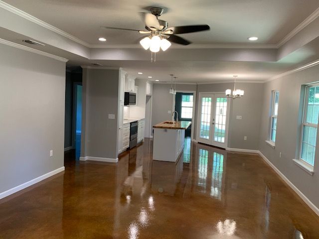 A living room with a ceiling fan and a kitchen in the background