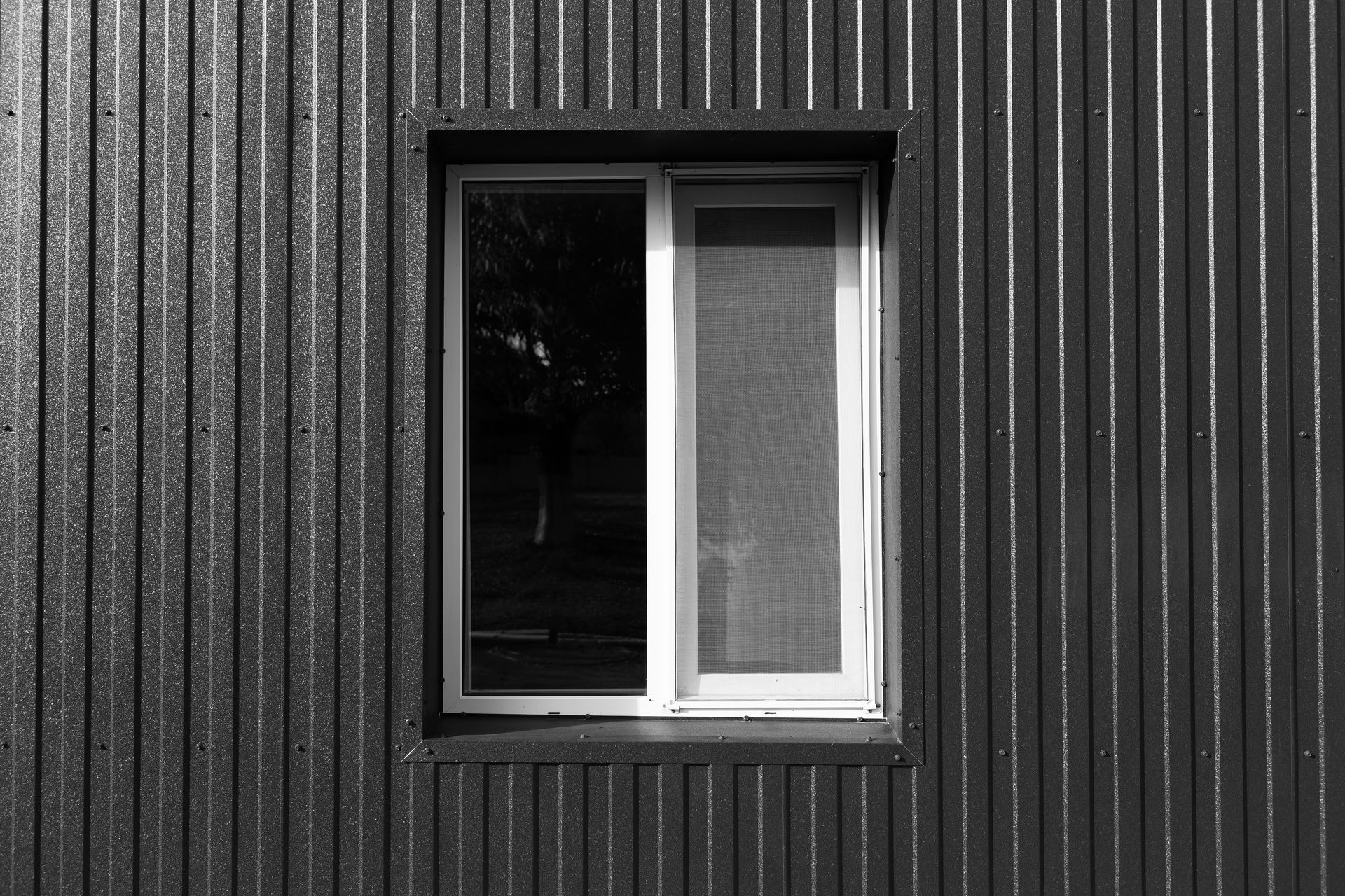 A black and white photo of a window on a black wall.