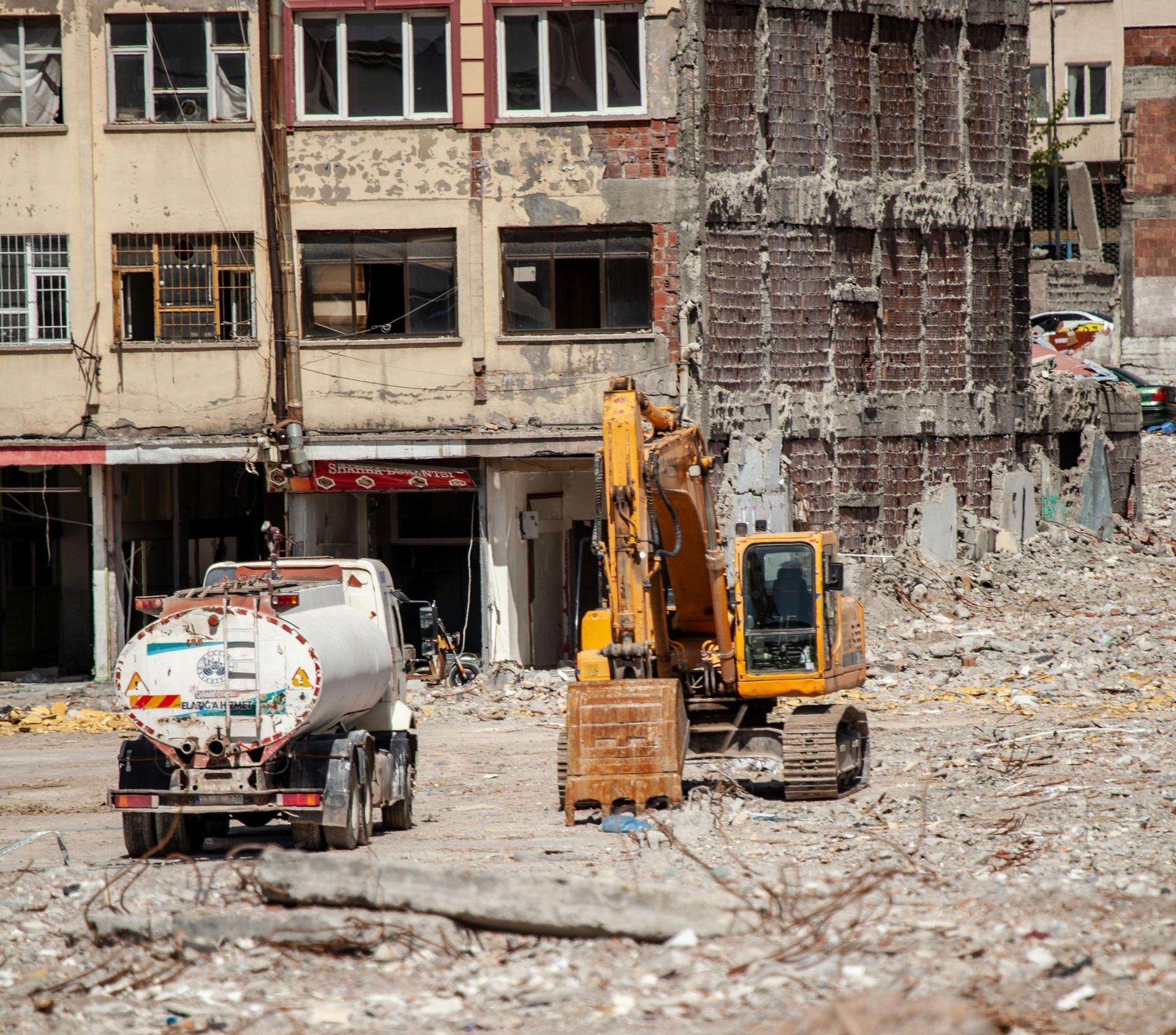 A tanker truck is parked in front of a building being demolished.