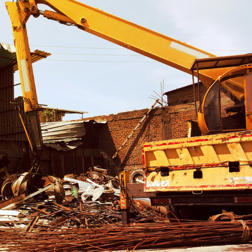A yellow crane is lifting a pile of scrap metal