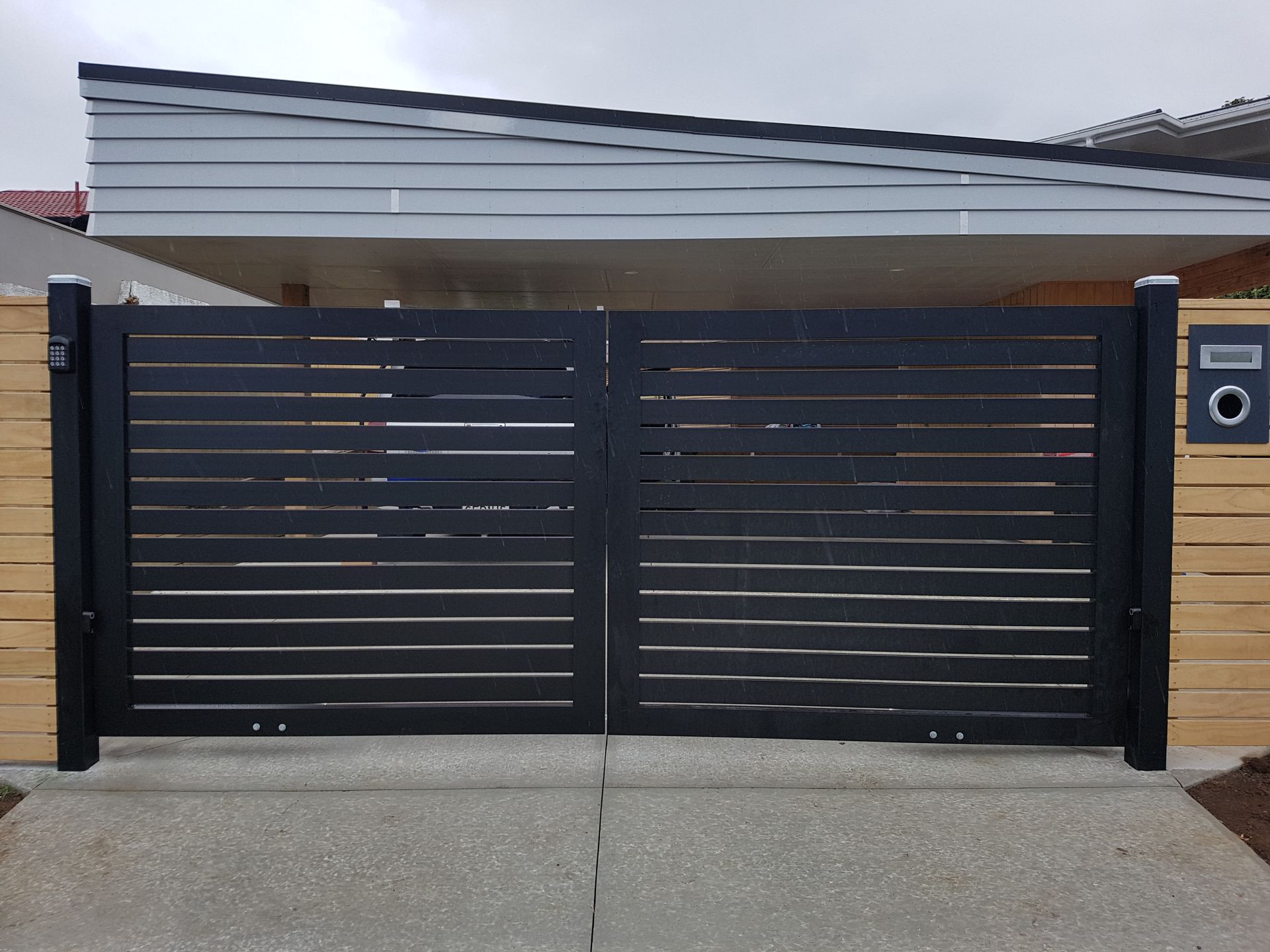 A house with a black gate and a mailbox in front of it