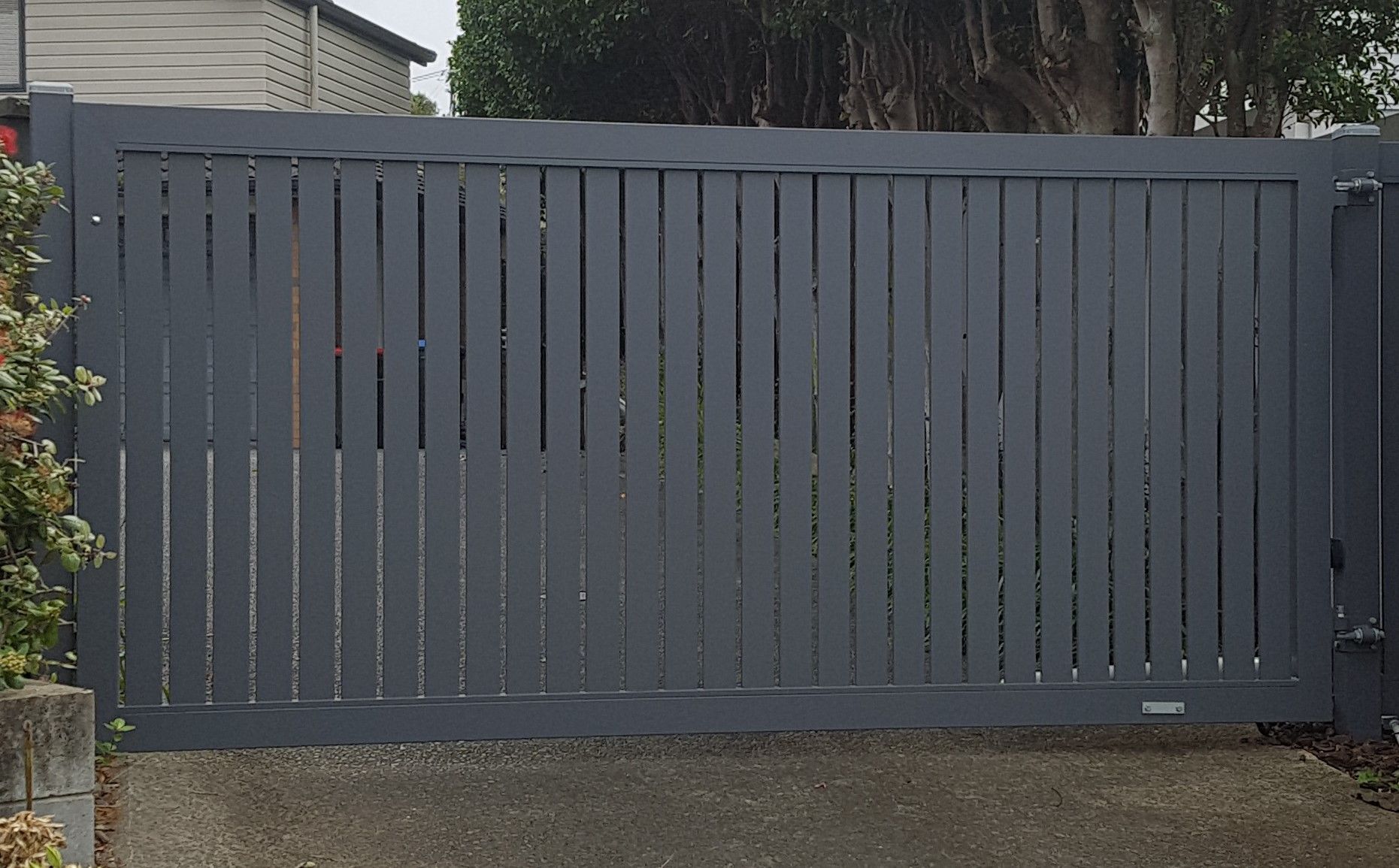 A gray fence is sitting in front of a house.