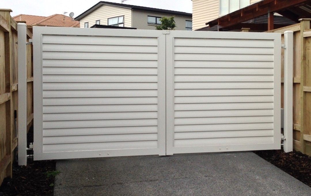 A white gate with a wooden fence behind it