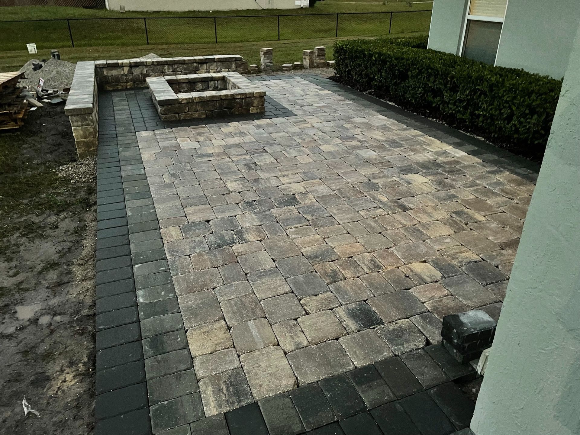 Stone patio with a low raised seating area and surrounding lawn beside a house