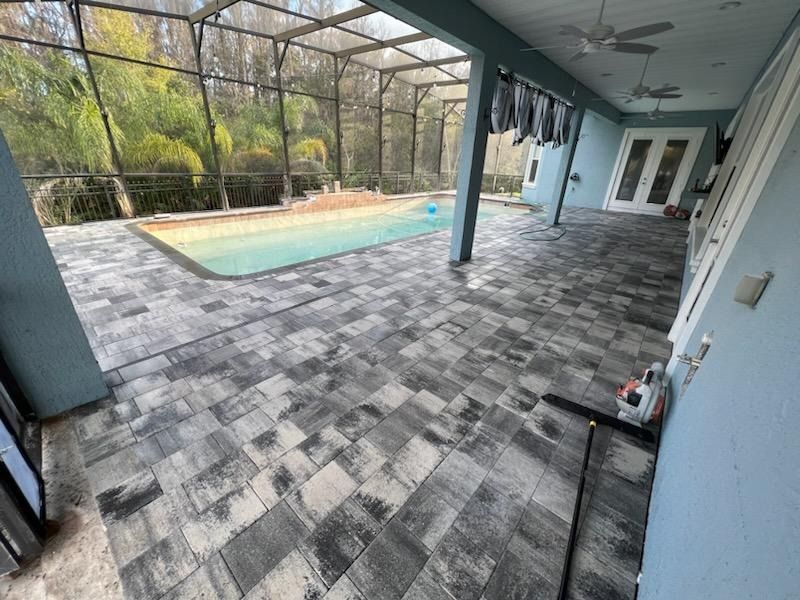 Screened patio with gray pavers, ceiling fan, and a pool view outside