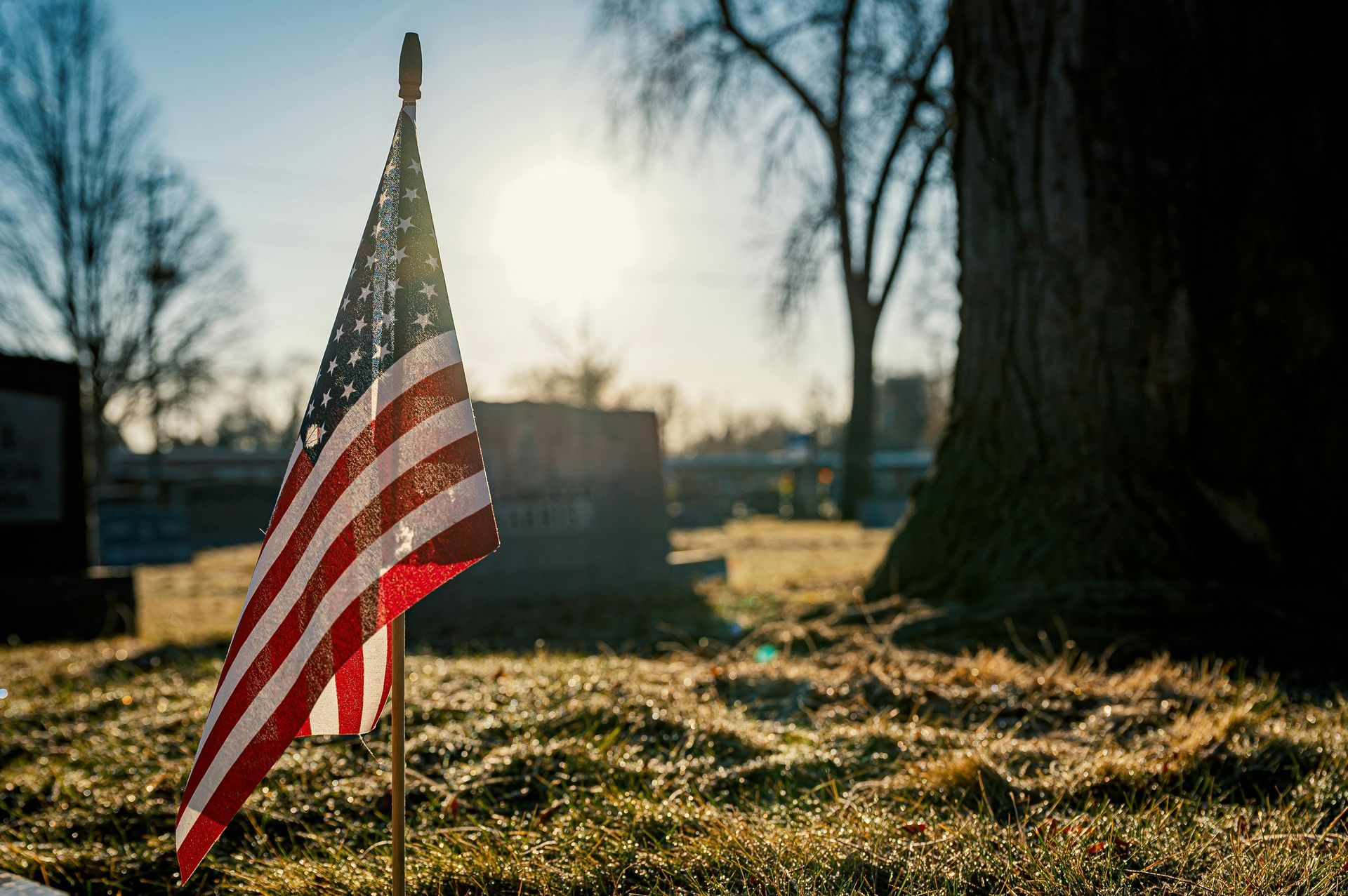 A man is holding an american flag over a coffin at a funeral.