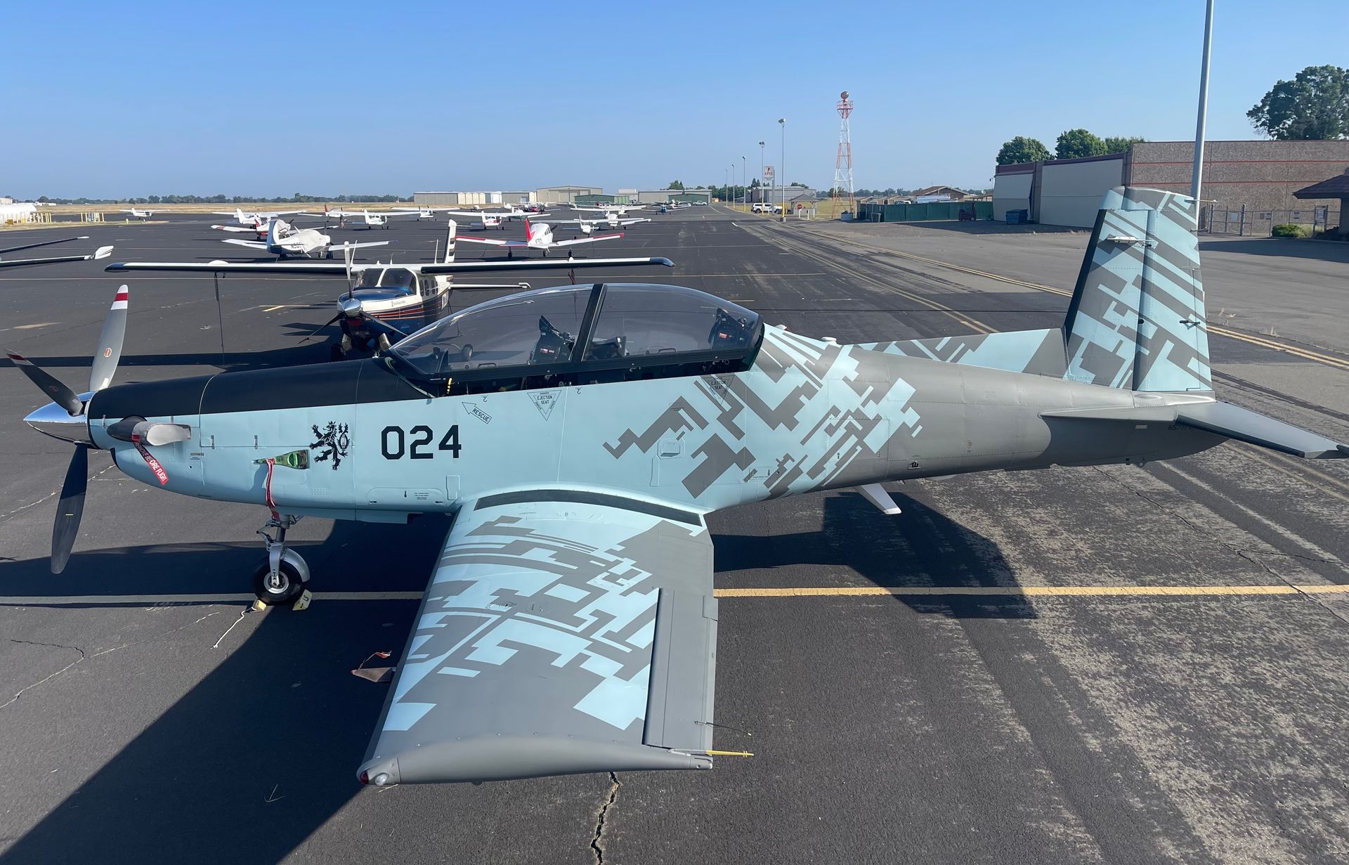A bright green and black stunt plane's wings and tail, set in a workshop with checkered wings.