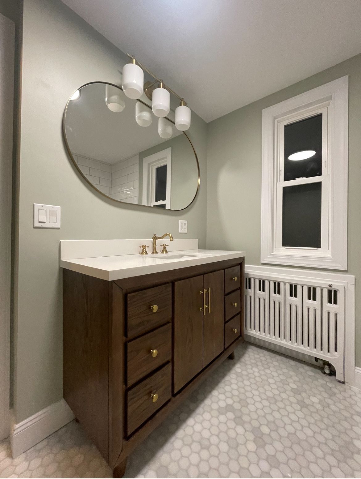 A bathroom with a sink , mirror and radiator.