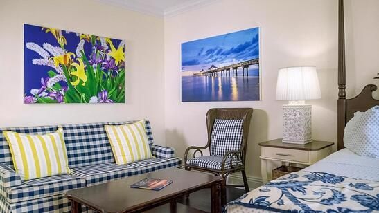 A living room with a couch , chair , table and paintings on the wall.