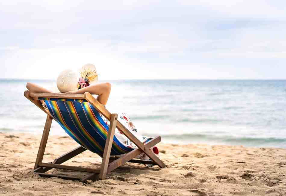 A woman is sitting in a beach chair on the beach.