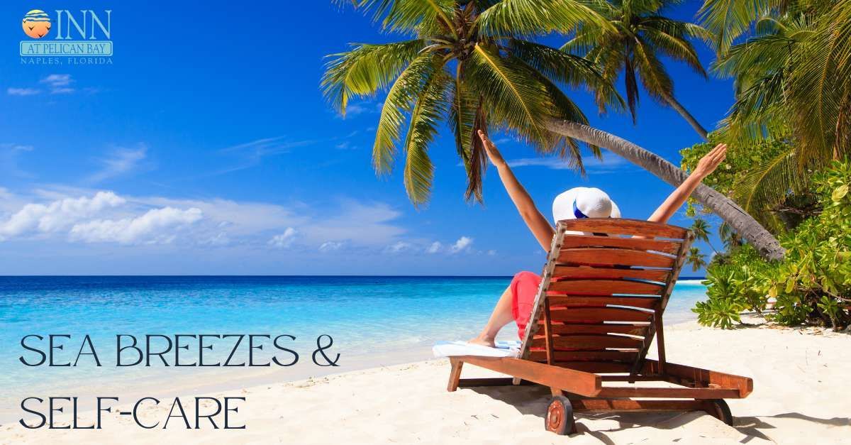 A woman is sitting in a chair on the beach with her arms outstretched.