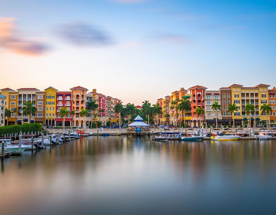 A marina with boats docked in front of a row of buildings.