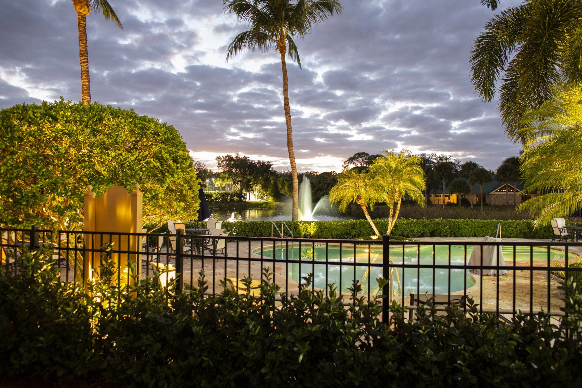 A fence surrounds a swimming pool with a fountain in the background