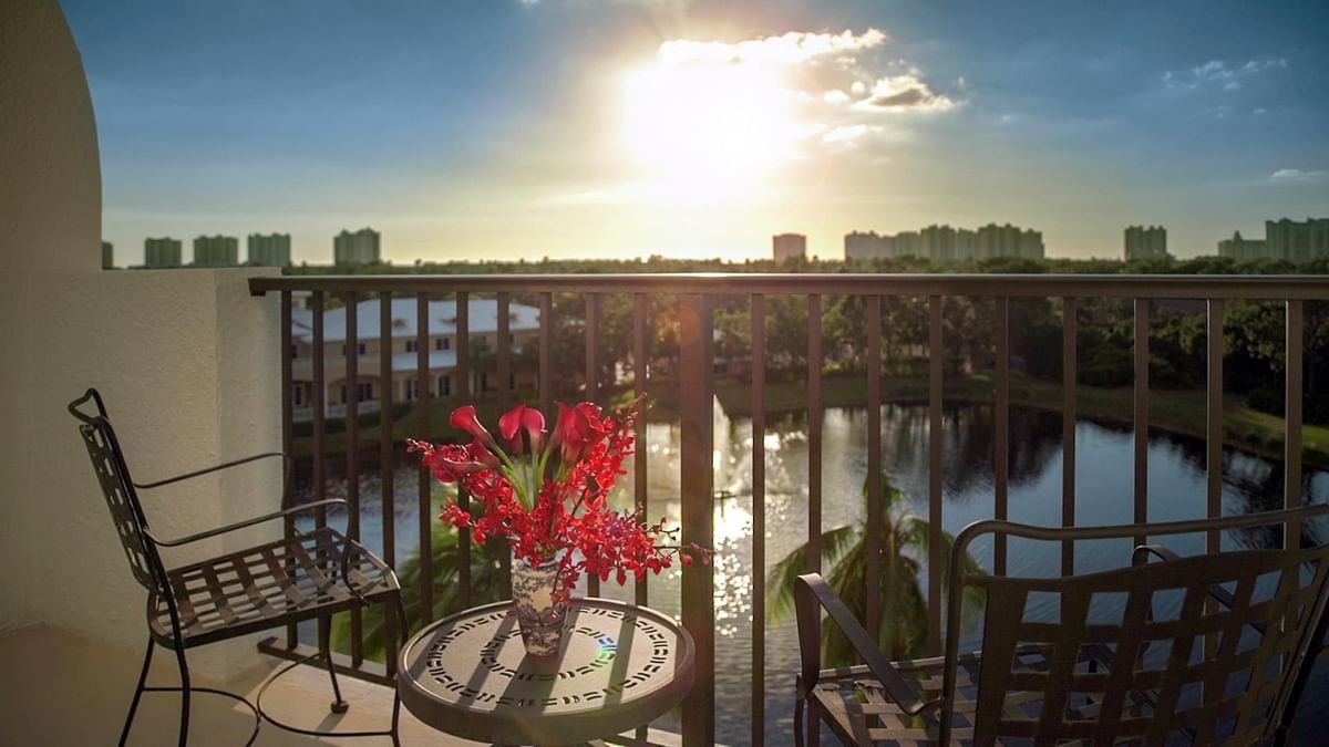 A balcony with a table and chairs overlooking a body of water.