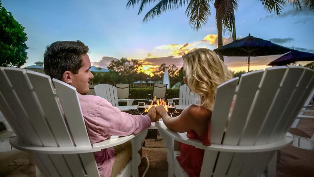 A man and a woman are sitting in lawn chairs holding hands.