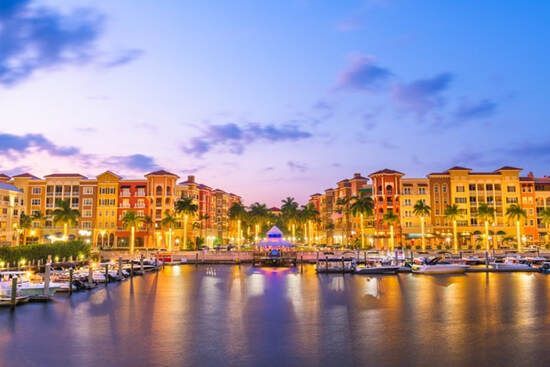 A marina with boats docked in front of a building at night.