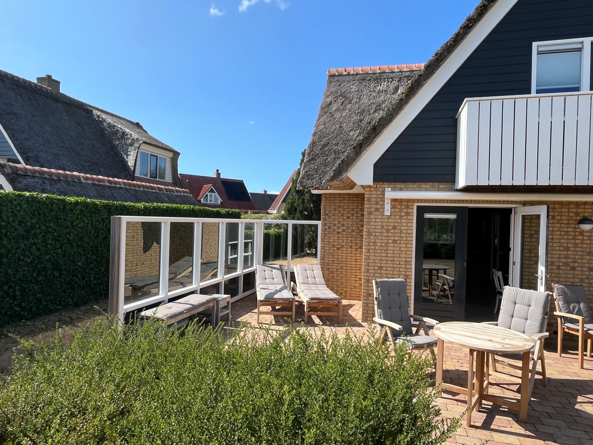 Terras van recreatievilla Vogelmient 15 met houten tuinmeubelen en uitzicht op de omgeving