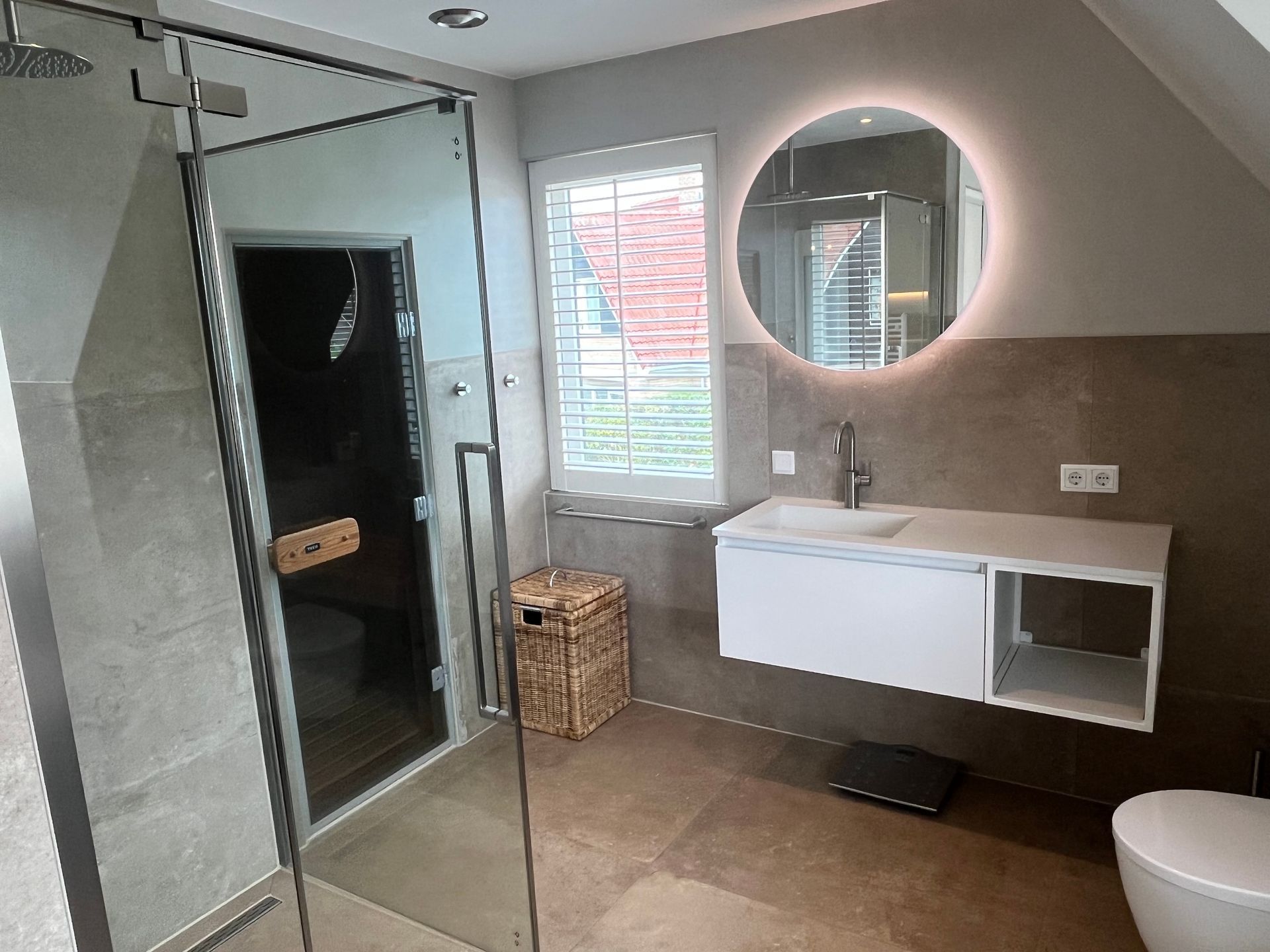 Moderne badkamer van recreatievilla Vogelmient 15 met glazen douchecabine, ronde wandspiegel en wastafelmeubel