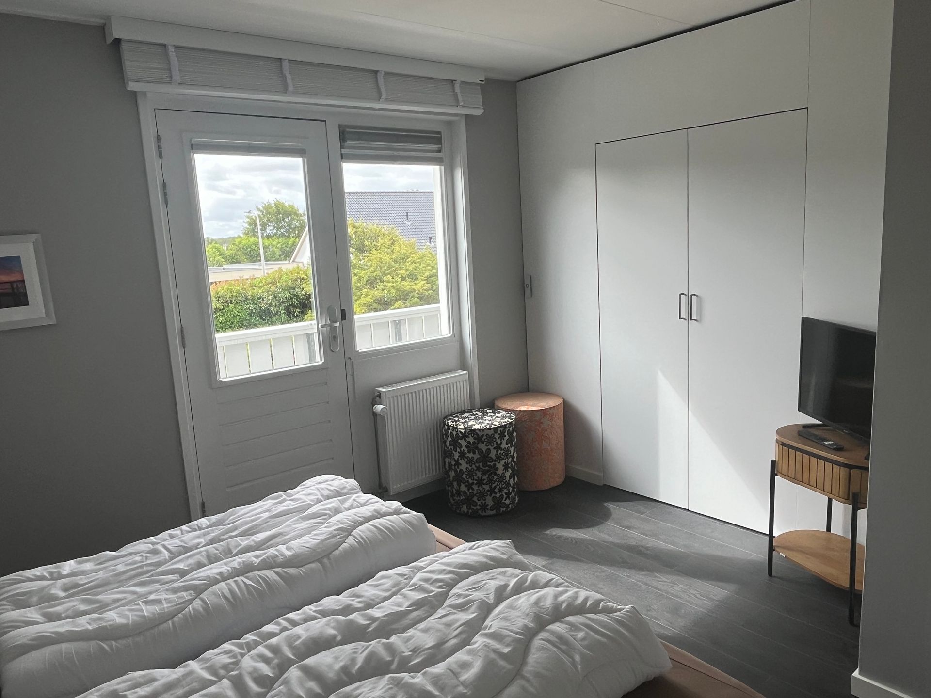 Slaapkamer van recreatievilla Vogelmient 15 met bed, witte kledingkast en uitzicht door het raam