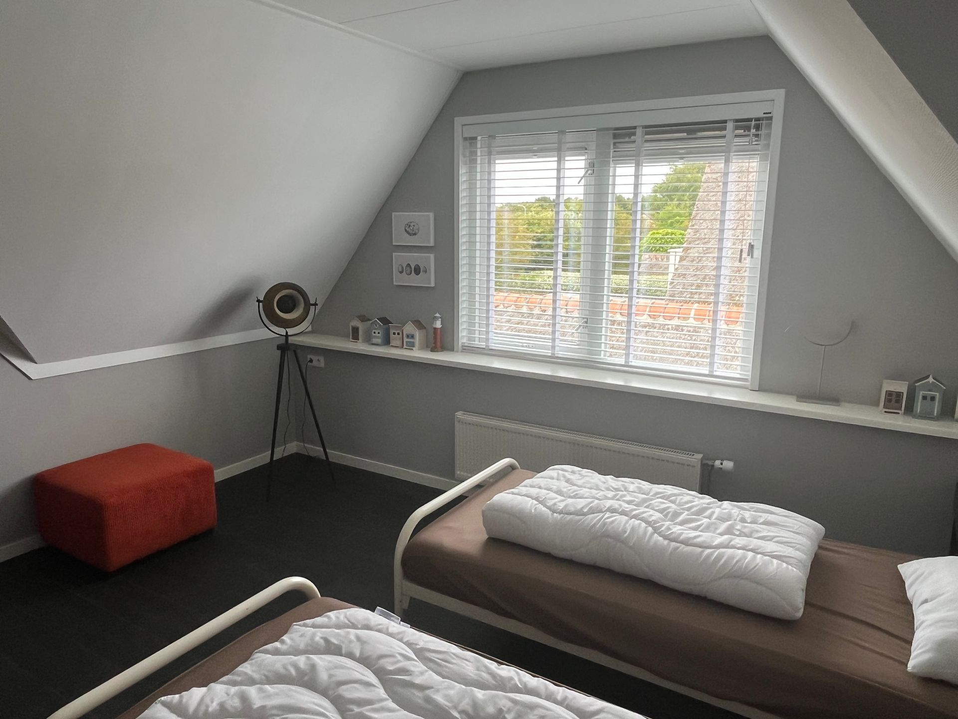 Slaapkamer van recreatievilla Vogelmient 15 met twee bedden, grijze muren en oranje poef