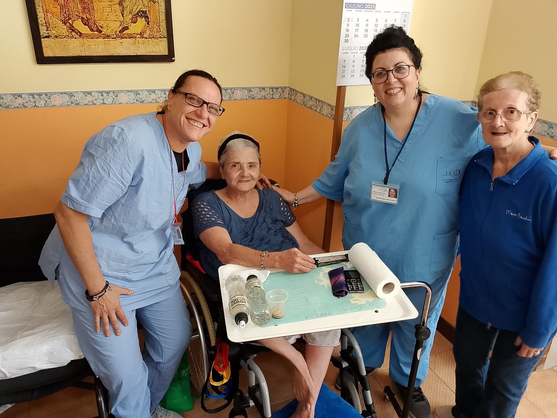 Quattro persone in una stanza, sorridenti intorno a una persona seduta che regge un vassoio di torta decorato.