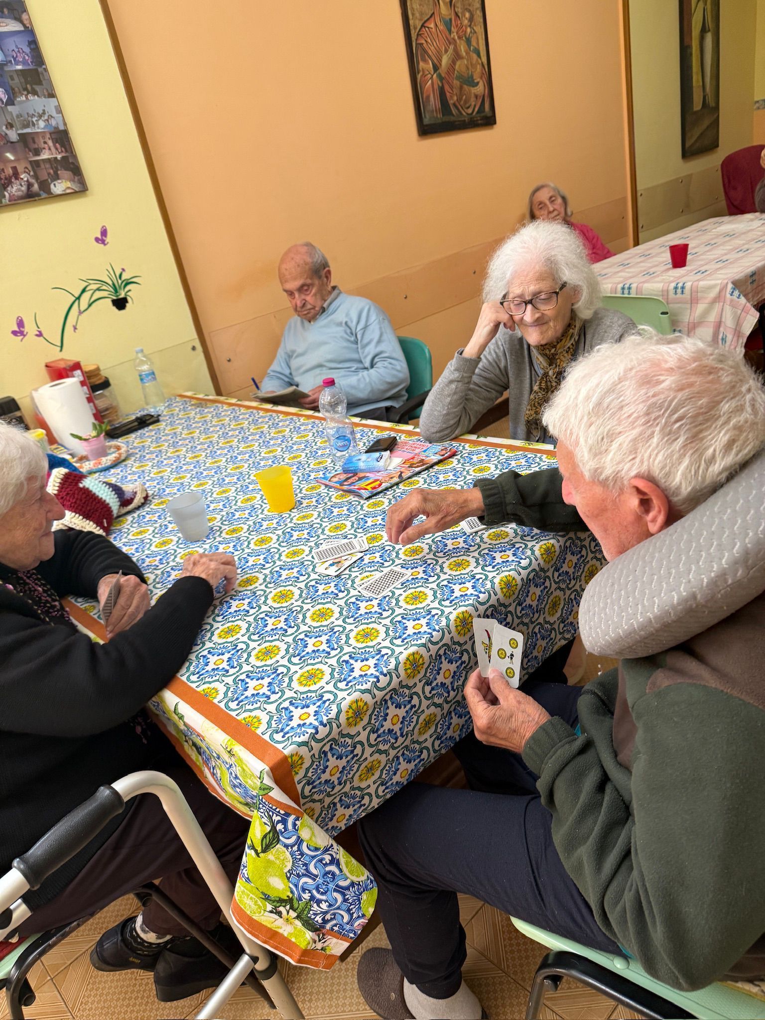 In un accogliente salotto, alcune persone si sono riunite attorno a un tavolo per giocare a carte.