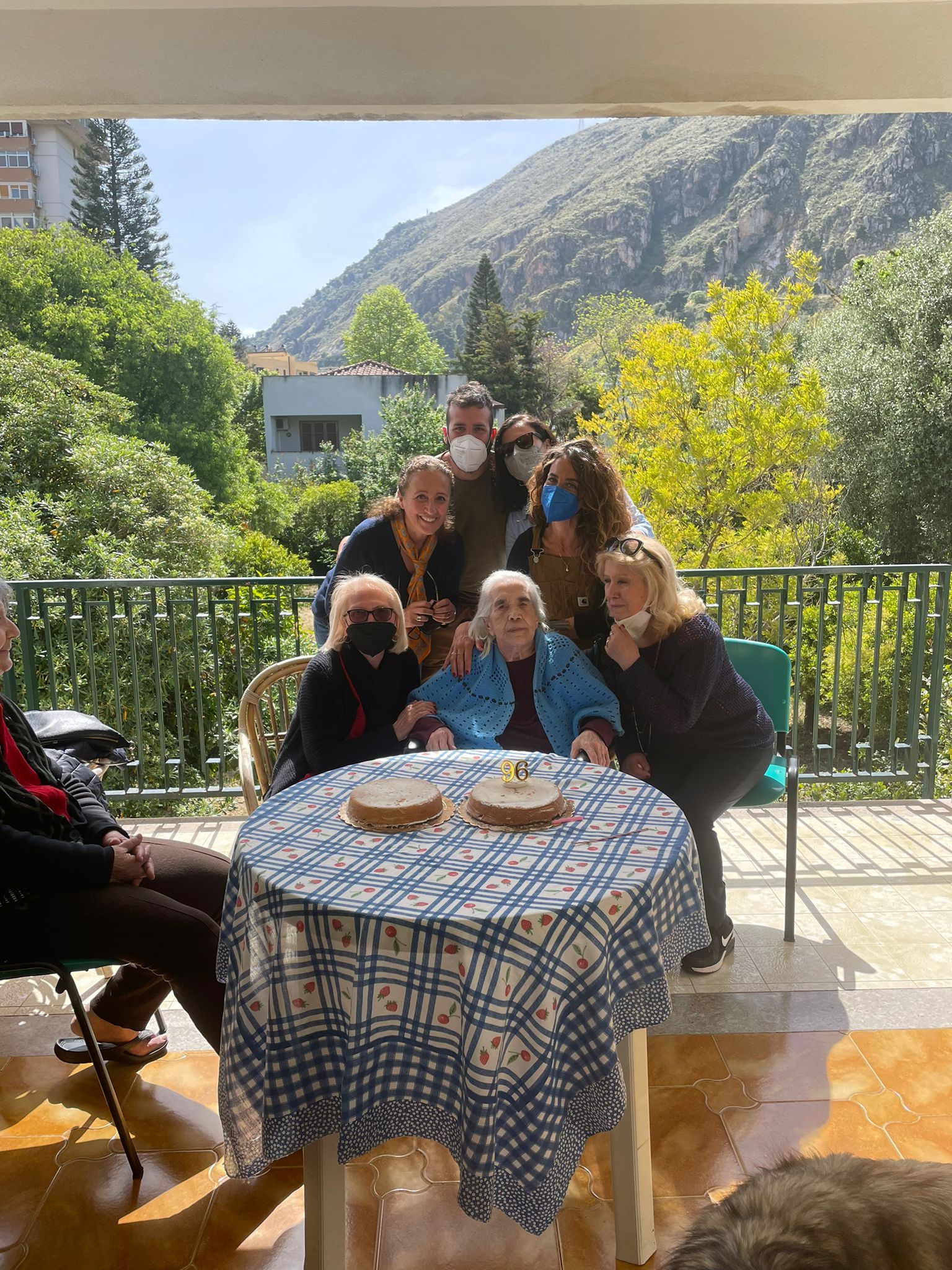 Gruppo seduto a un tavolo all'aperto su un patio soleggiato con vista sulle montagne.