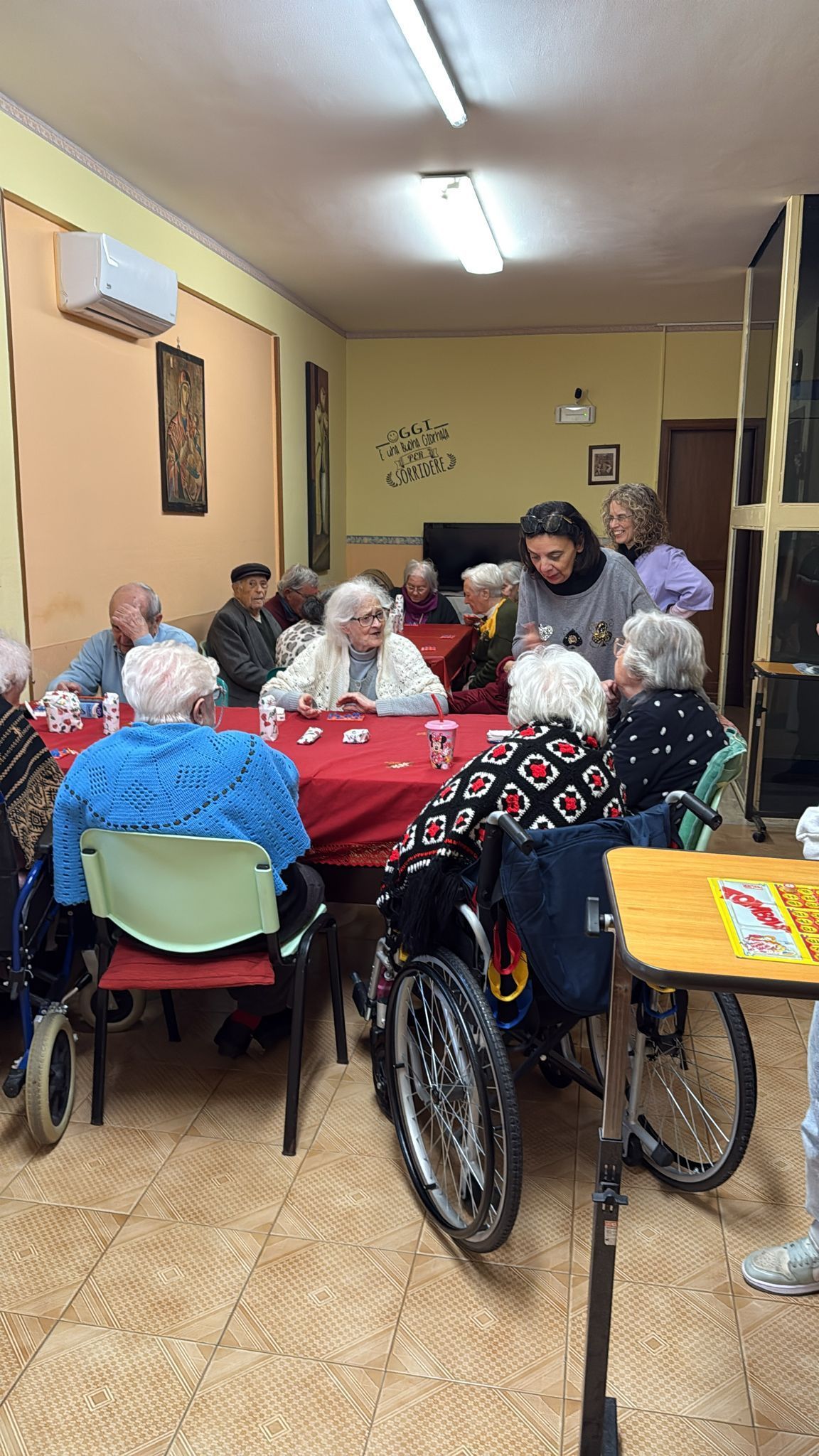 Il gruppo si è riunito attorno a dei tavoli in una sala comune, con una sedia a rotelle in primo piano.