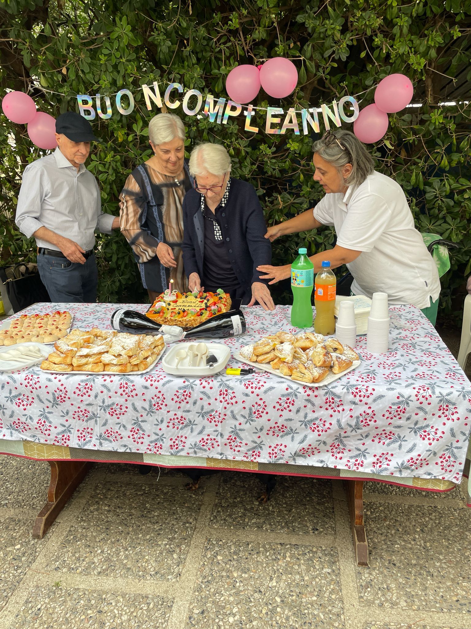 Durante una festa all'aperto, le persone si sono riunite attorno a un tavolo da picnic con torte e palloncini.