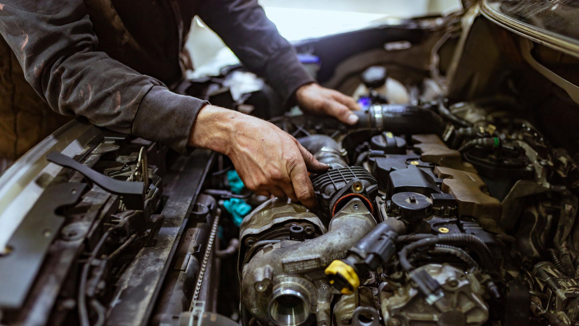 A man is working on the engine of a car.