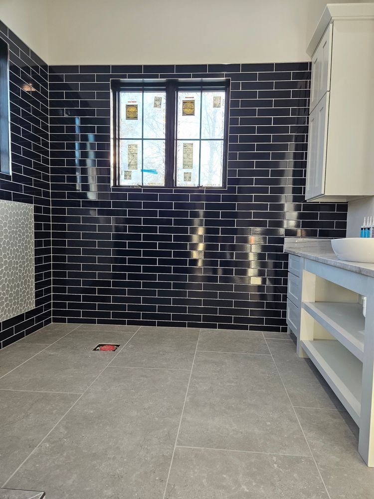 Bathroom with black subway tile walls, gray floor tile, a window, and a light blue vanity.