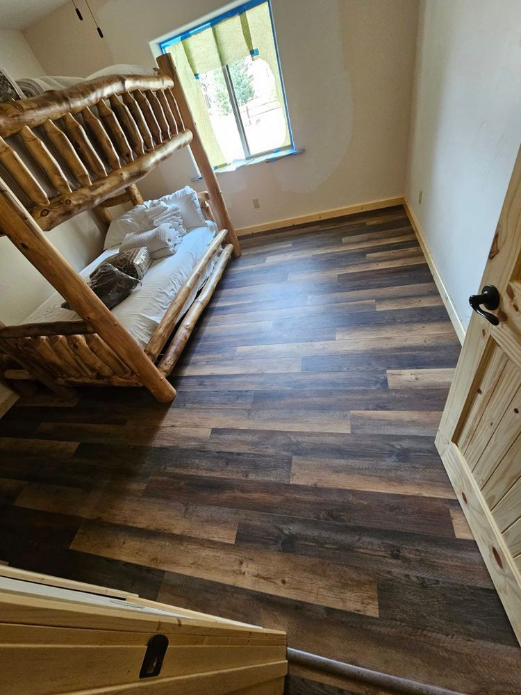 Bedroom with wood-look flooring, a wooden bunk bed, and a closed wooden door.