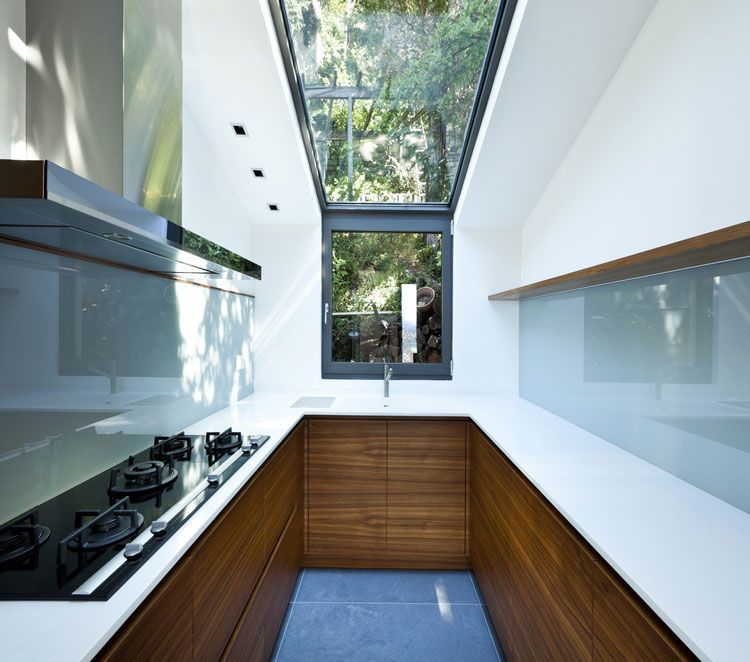 A kitchen glass splashback with a stove top oven and a window