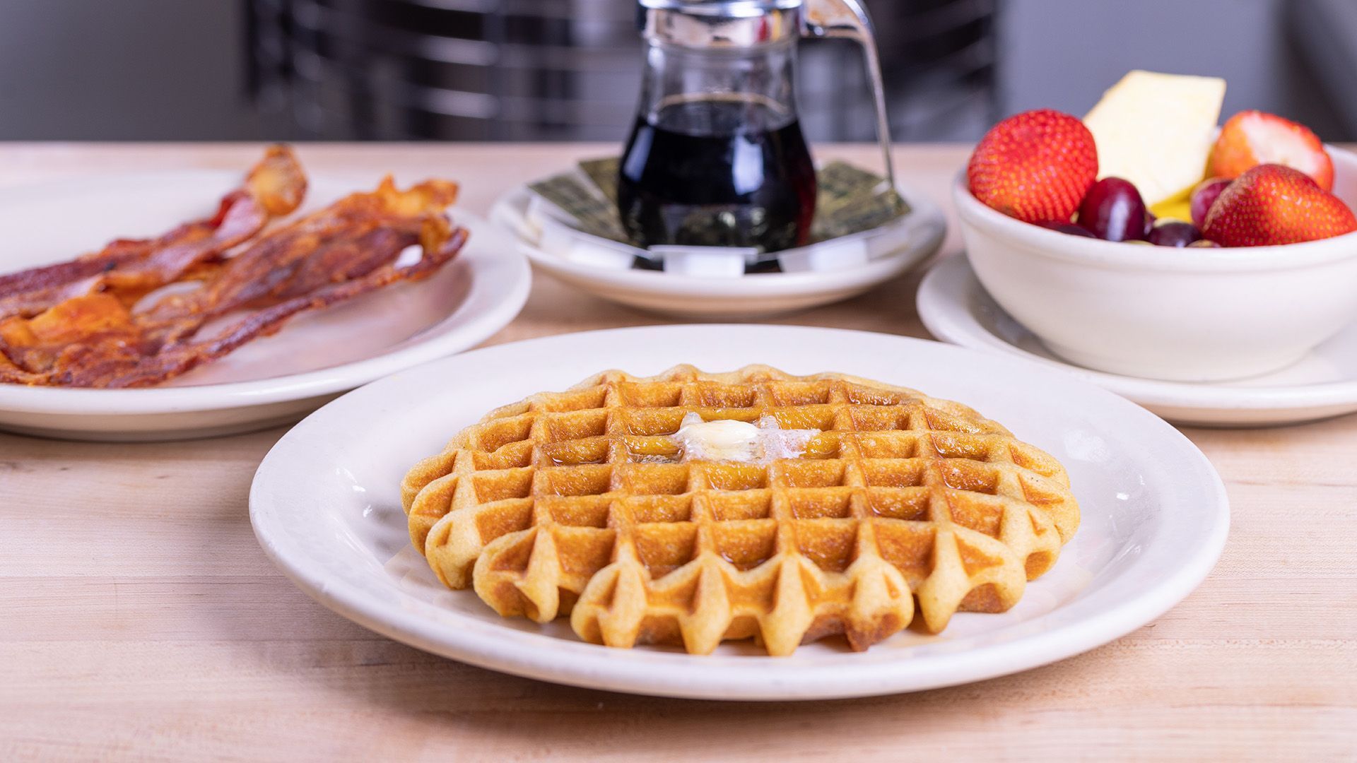 Gluten-free waffle on a plate with fresh strawberries and crispy bacon at Savoy